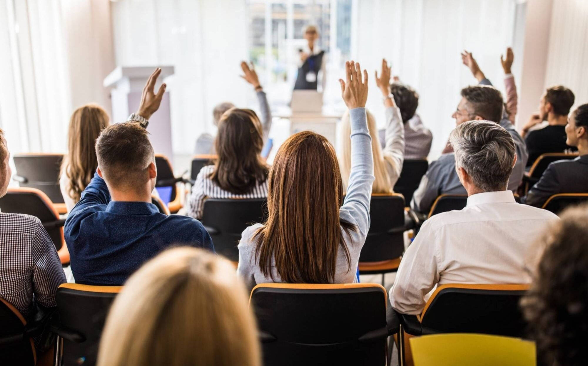 People sitting in chairs with their hands raised